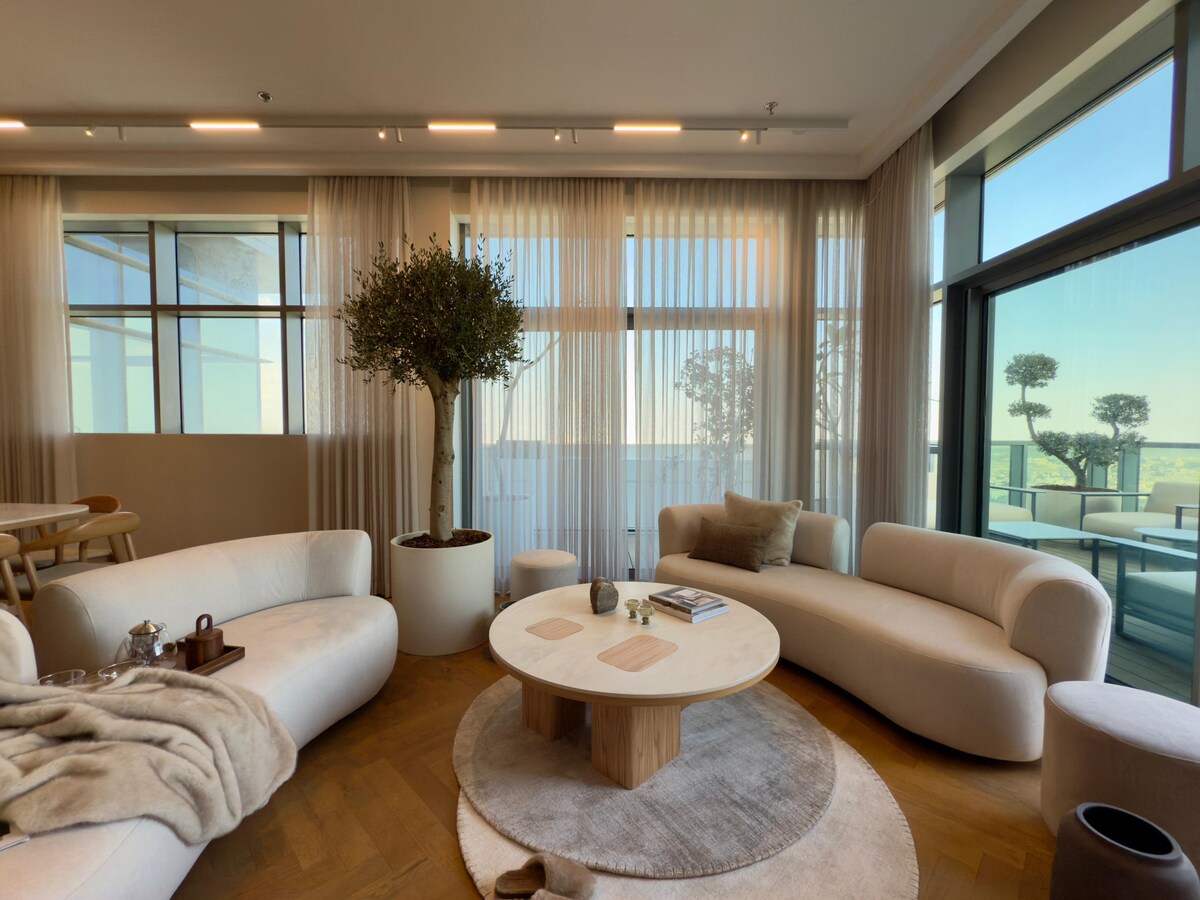 Elegant living room with curved sofas and floor-to-ceiling city-facing windows